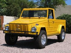 a yellow jeep is parked in the gravel