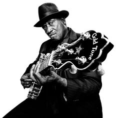 a black and white photo of a man holding a guitar