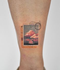 a person with a small stamp on their leg that has a house in the clouds