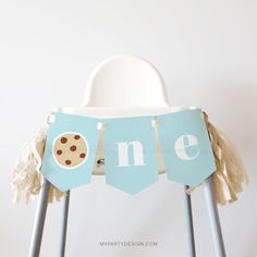 a blue one banner with chocolate chip cookies hanging from it's legs on a chair