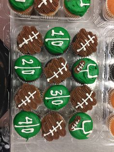 cupcakes decorated with green and white frosting are in a plastic container on the table