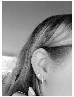 black and white photograph of a woman with ear piercings on her ears, looking out the window