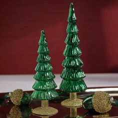 three green glass christmas trees sitting on top of a table next to each other,