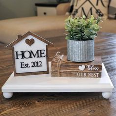 a white tray topped with a potted plant next to a wooden sign that says home est 2012