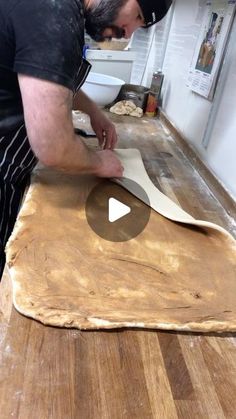 a man is making pizza dough on a wooden table