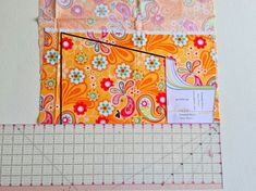 a piece of fabric next to a ruler on a white surface with an orange and pink flowered design