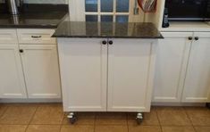 a kitchen with white cabinets and black counter tops on casteors to the door way