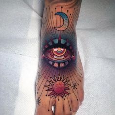 a person's foot with an eye and sun tattoo on it