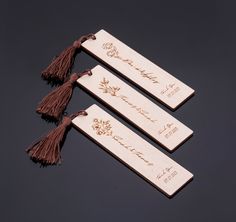 three wooden bookmarks with tassels and writing on them sitting on a table