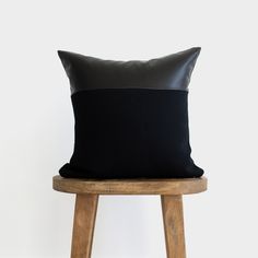 a black pillow sitting on top of a wooden stool