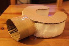 a roll of toilet paper sitting on top of a wooden table next to a piece of cardboard