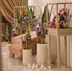 three vases filled with colorful flowers sitting on top of a white floor next to a chair