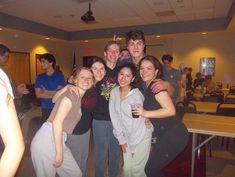 a group of young people standing next to each other in a room with tables and chairs