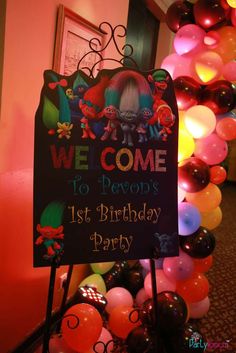 a welcome sign with balloons in the background