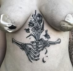 a woman's stomach with flowers and bones tattooed on her side, in black ink