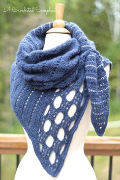 a white mannequin wearing a blue knitted shawl with holes on it