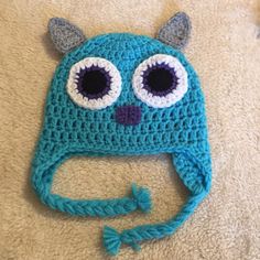 a blue crocheted hat with eyes and horns on it's head is laying on the floor