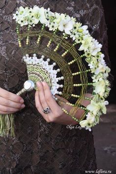 a close up of a person holding a fan with flowers on the front and side