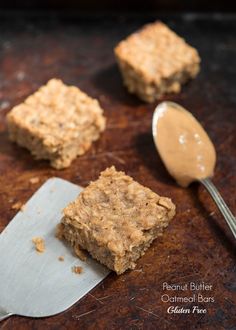 some food is sitting on top of a table with a spoon next to it and two squares of oatmeal