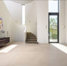 an empty living room with stairs leading up to the second floor and a painting on the wall