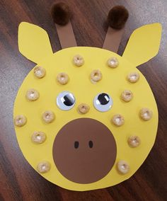 a paper plate shaped like a giraffe with doughnut holes on its face