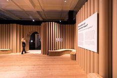 a person standing in front of a wall with wooden slatted walls and benches