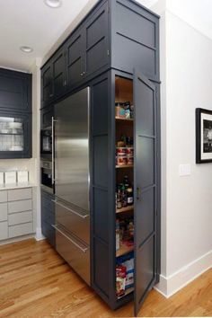 a large pantry in the middle of a kitchen with stainless steel appliances and wood flooring