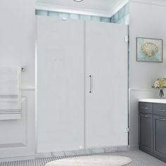 a bathroom with a walk in shower next to a white sink and gray cabinetry