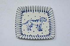 a small blue and white plate with a dog on it's side, in the shape of a rectangle