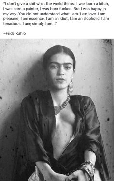 an old photo of a woman with jewelry on her neck and chest, sitting in front of a wall