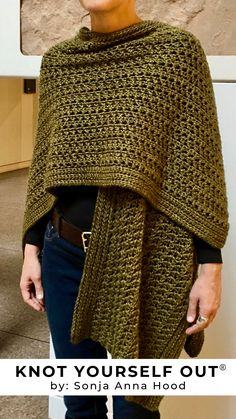 a woman wearing a green knitted shawl with the words knot yourself out written on it