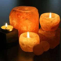 three lit candles sitting next to each other on a black counter top with an object in the background