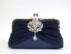 "Please always inform me about your event day, Thank you You can see this clutch on my YouTube channel: https://www.youtube.com/watch?v=dv0Eb3TZNc8&feature=youtu.be This elegant clutch is made from pure silk fabric. It is featuring flowing chiffon silk and a diamond brooch. I use pure dupioni silk for the body of the clutch as the silk fabrics have a crisp texture and beautiful sheen. Dupioni silk has an irregular weave with tiny nubs showing. One of the oldest luxury fabrics, popular for weddin Navy Blue Clutch, Navy Clutch, Elegant Clutch, Brooch Wedding, Silk Clutch, Hand Bags For Women, Blue Clutch, Dupioni Silk, Silk Fabrics