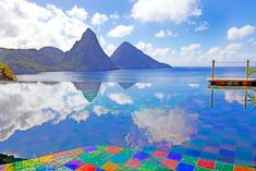 a colorful bench sitting on the edge of a large body of water with mountains in the background