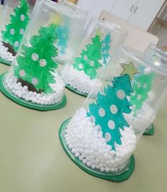 plastic cups with christmas trees in them on a table