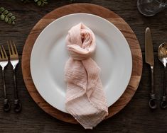 a white plate topped with a pink scarf next to silverware