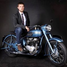 a man in a suit and tie sitting on top of a blue motorbike