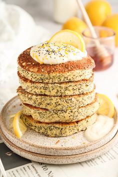 a stack of pancakes on a plate with lemons and poppy seed sprinkles