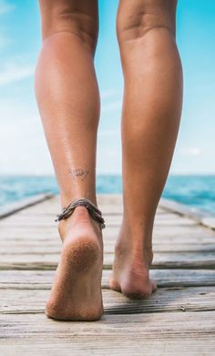 a woman's bare legs and feet on a pier