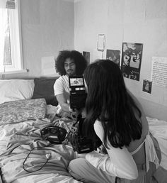 two people sitting on a bed looking at a camera