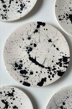 four black and white plates with paint splattered on them