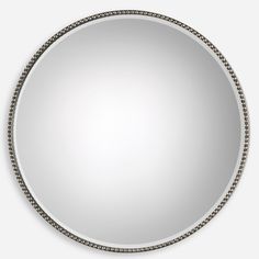 a round mirror with beaded trim around the edges and an oval frame, on a white background