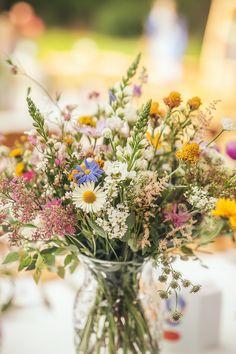 a vase filled with lots of flowers on top of a white tablecloth covered table