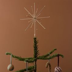 a small christmas tree with ornaments hanging from it's branches and an ornament on top