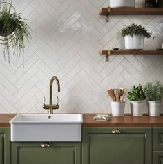 a kitchen with green cabinets and white tiled backsplash, brass faucet