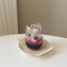 a glass filled with liquid sitting on top of a table next to an open book