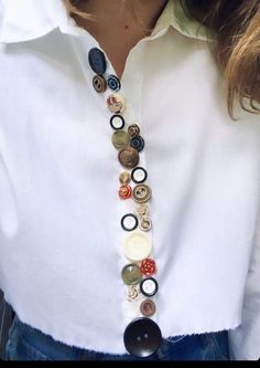 a close up of a person wearing a white shirt and a necklace with buttons on it