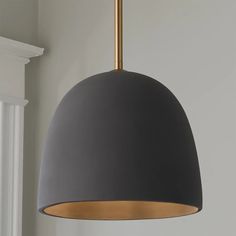 a black and gold pendant light hanging from the ceiling in a room with white walls