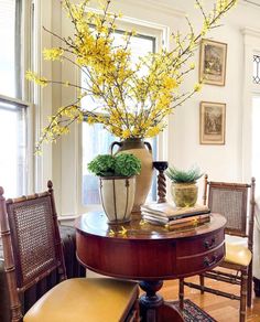 a vase with yellow flowers sitting on top of a table in front of a window