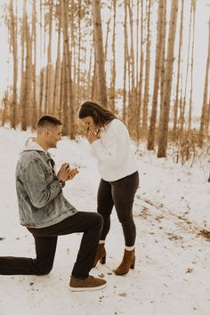 a man kneeling in the snow next to a woman who is holding her hands together